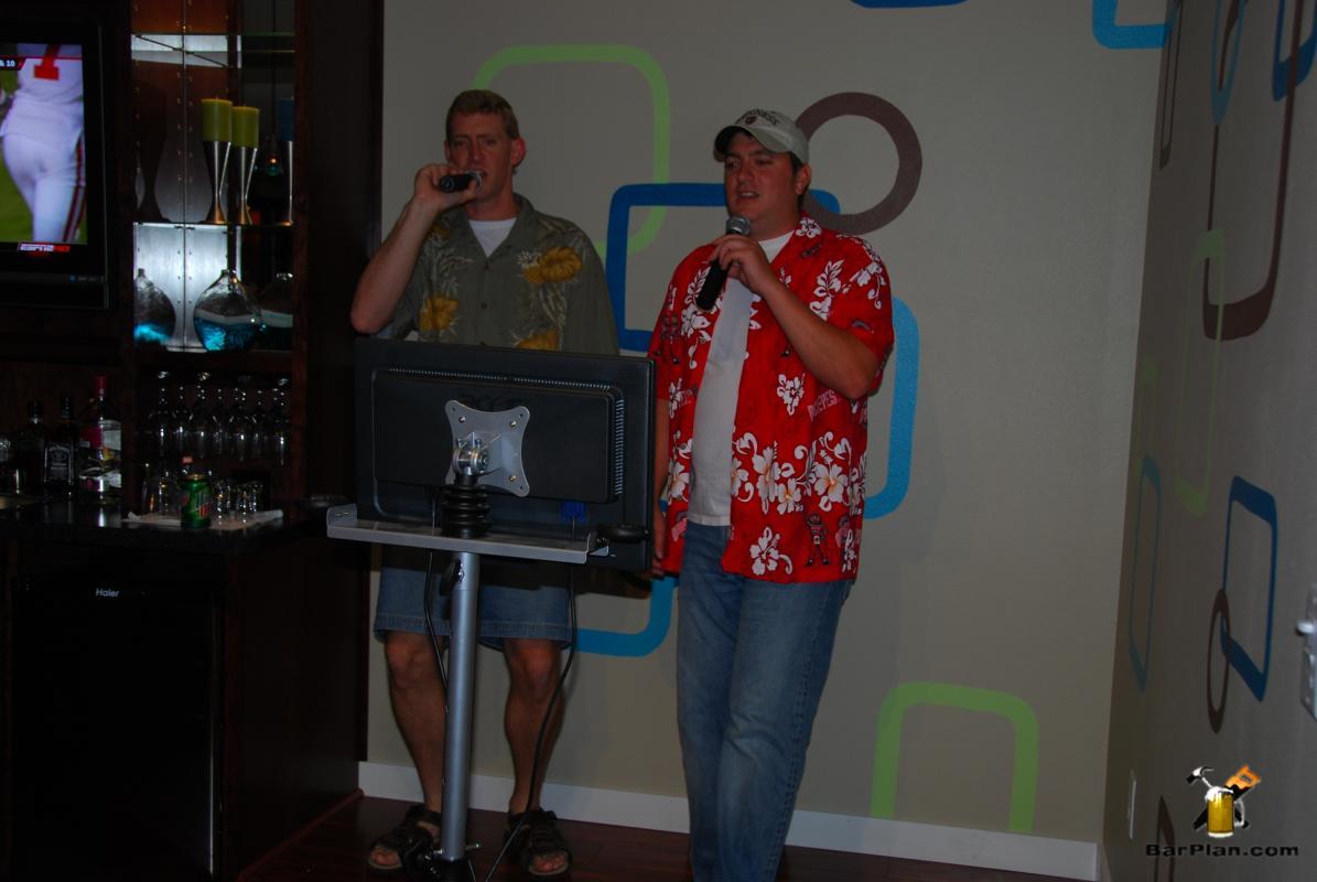 two men singing karaoke at home bar