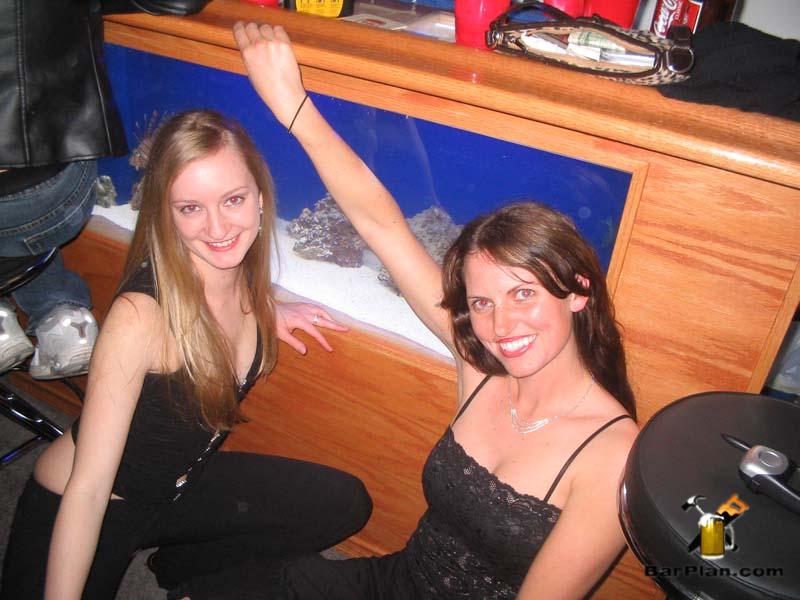 two girls sitting next to salt water fish tank bar